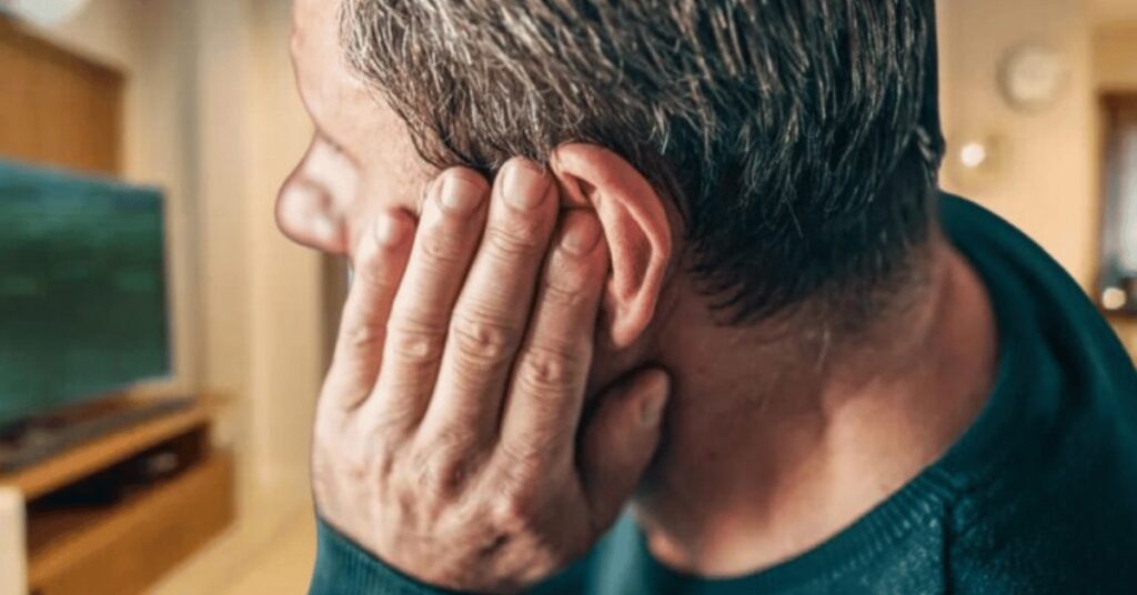 man blocking his ear from sound sensitivity, hyperacusis, or misophonia