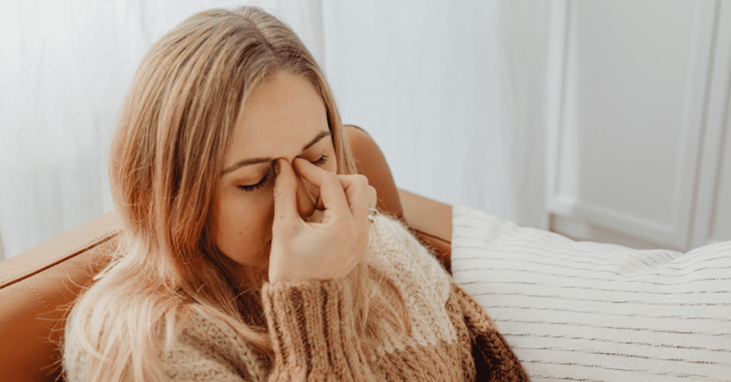 Woman holding the bridge of her nose from post nasal drip