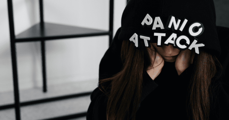Woman in a black hoodie with letters that say Panic Attack on the hood