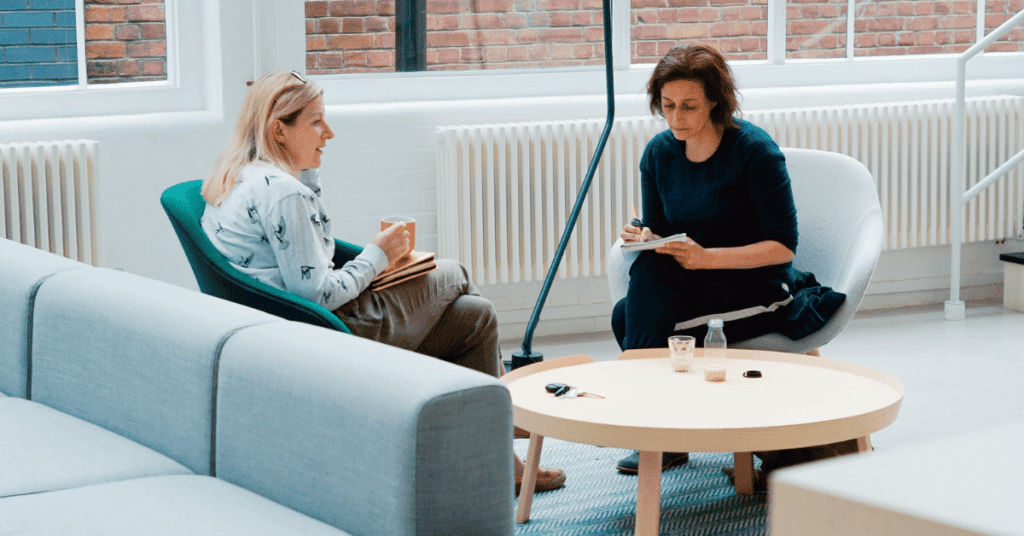 Two woman speaking to each other across a table