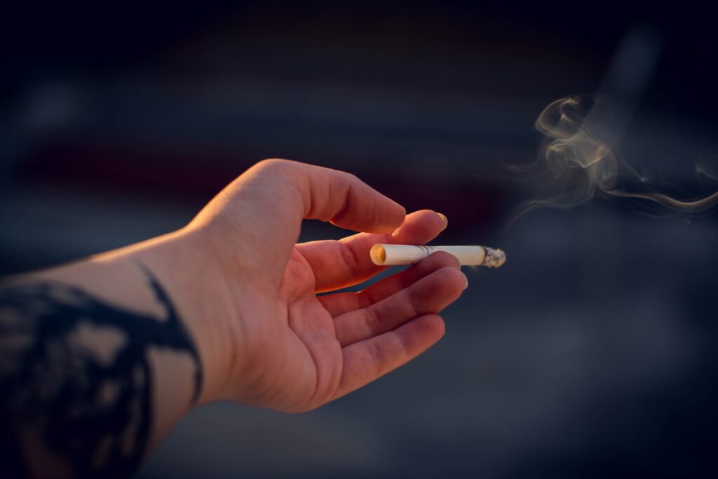 Person's hand holding a lit cigarette