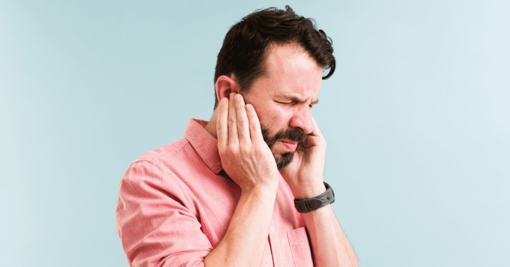 Man with an ear infection holding his ear in pain