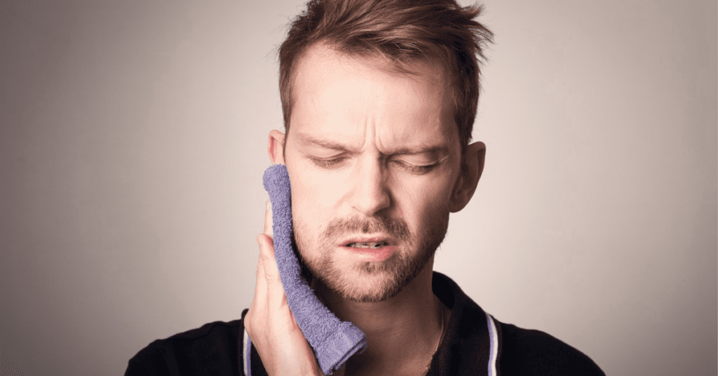 Man holding a towel on his face due to jaw pain