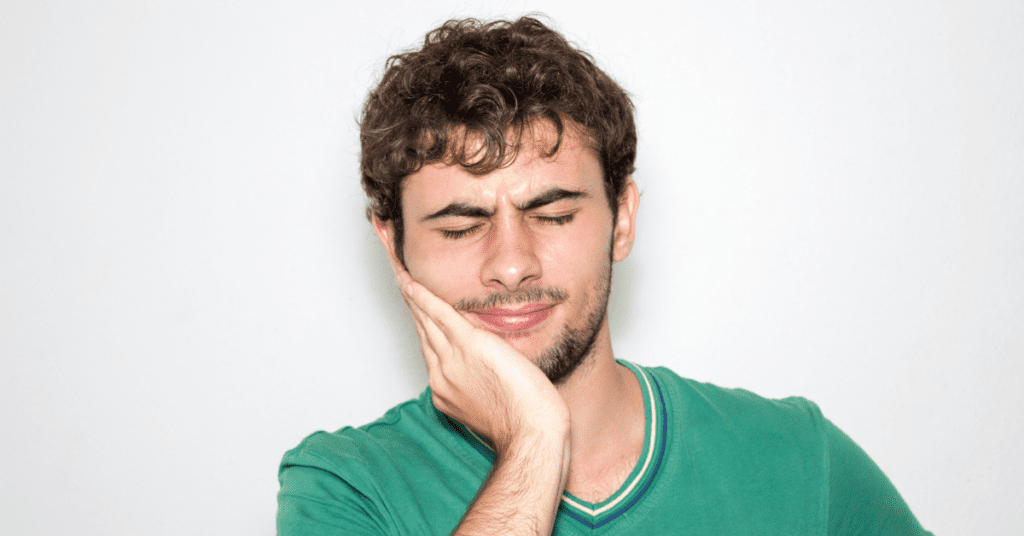 Man holding his jaw in pain due to TMJ issues