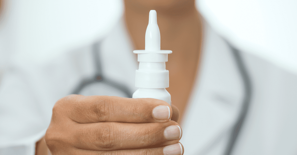 Hand holding a bottle of nasal spray.