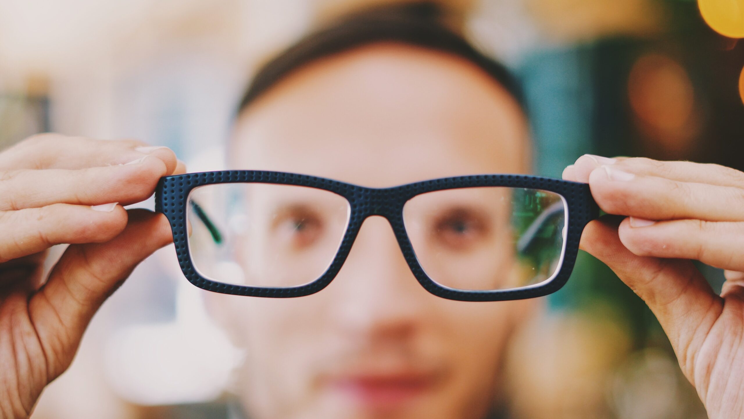 Blurry picture of a man holding his glasses in front of his face