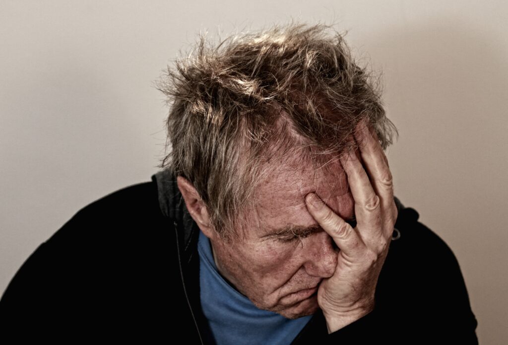 Old man with a headache holding his head in pain