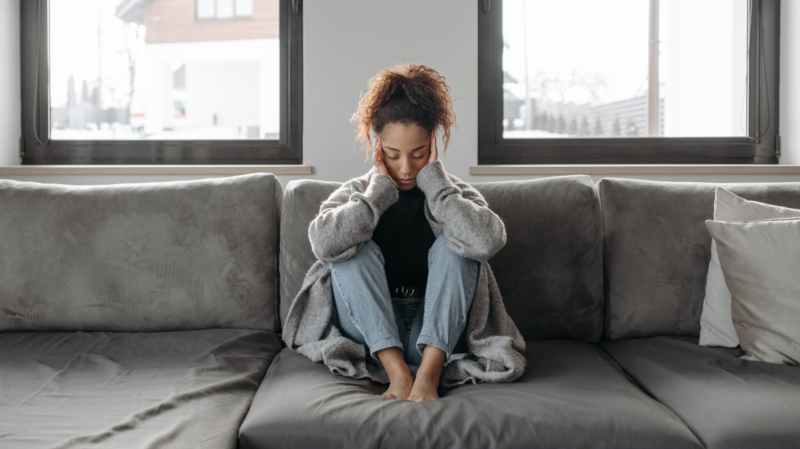 Woman sitting on the couch with her head resting in her hands