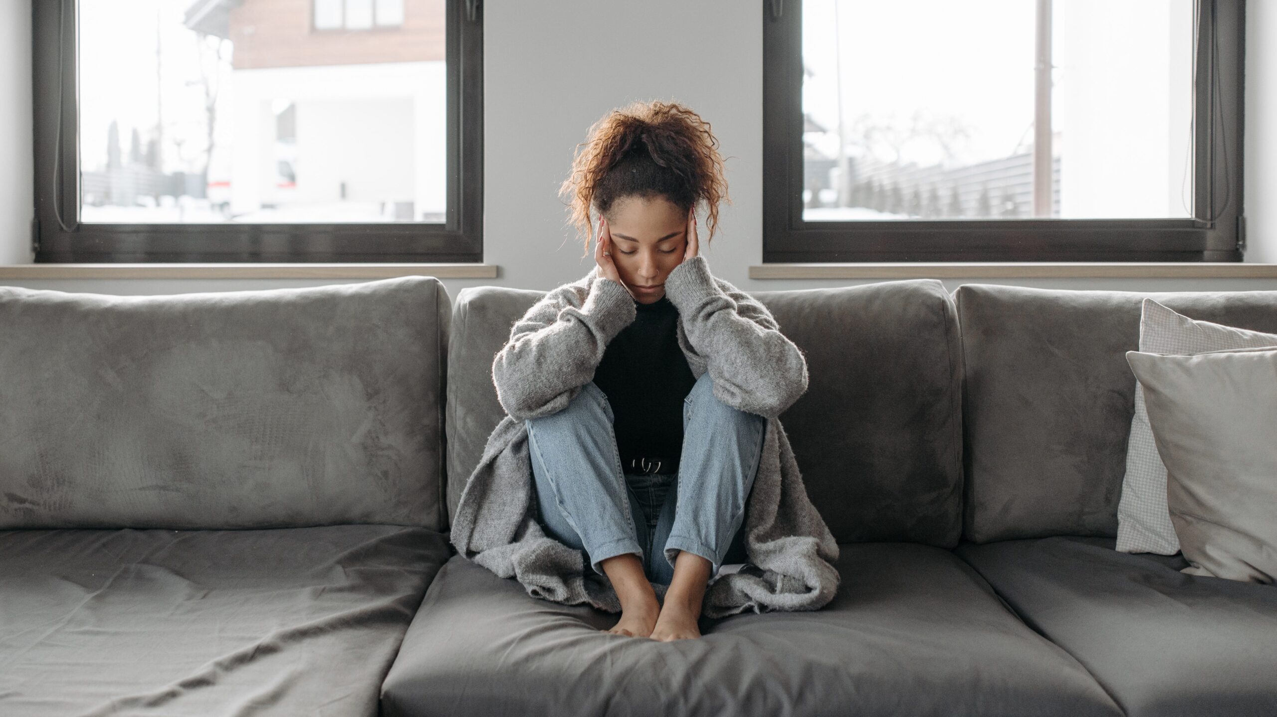 Woman sitting on the couch with her head resting in her hands 