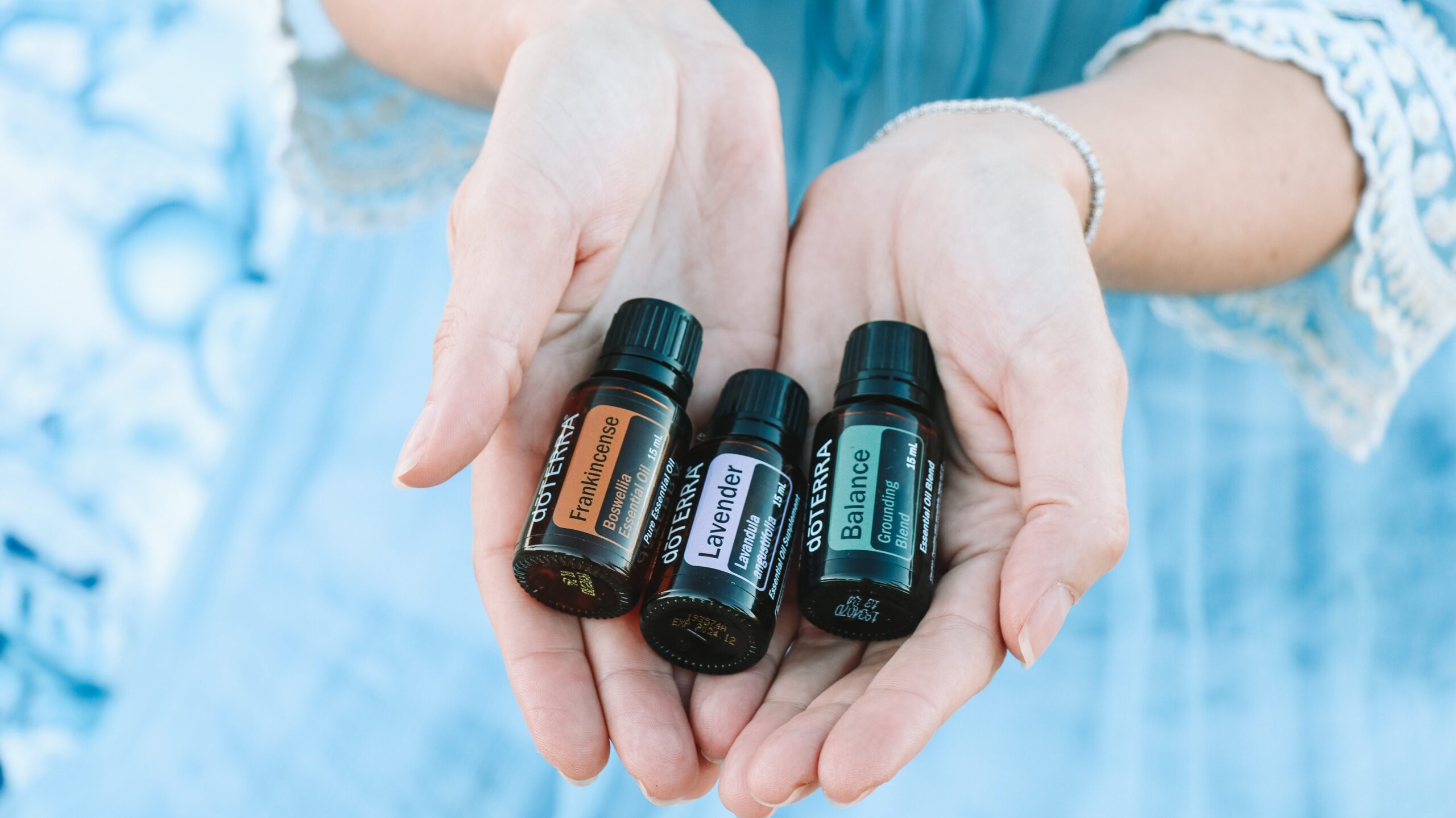 Hands holding a variety of essential oil bottles