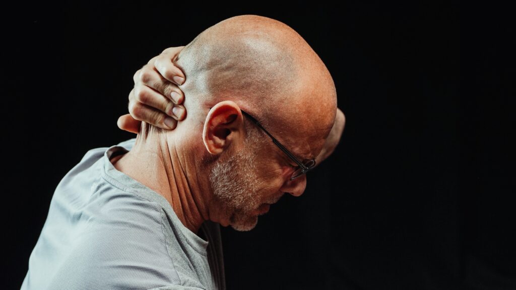 Man holding the back of his neck with his head down