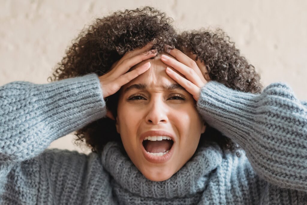 Woman holding her head with her mouth open