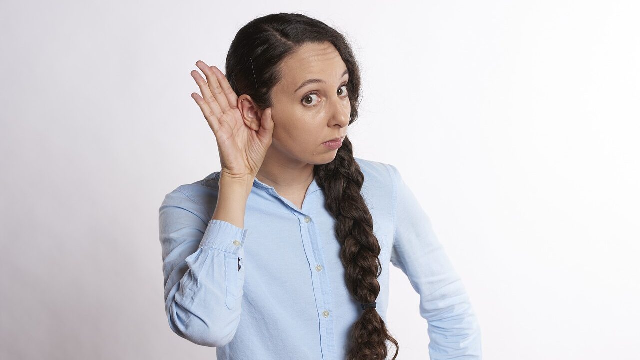 Woman holding her hand to her ear to help her hear more clearly 