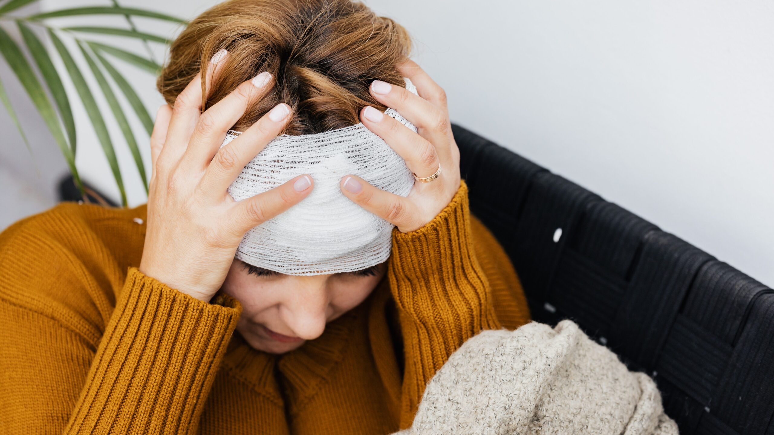 Woman with a head injury holding her head after wrapping it with a bandage