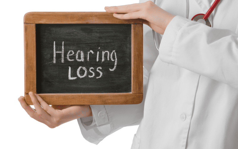 person holding up a chalkboard that says Hearing Loss