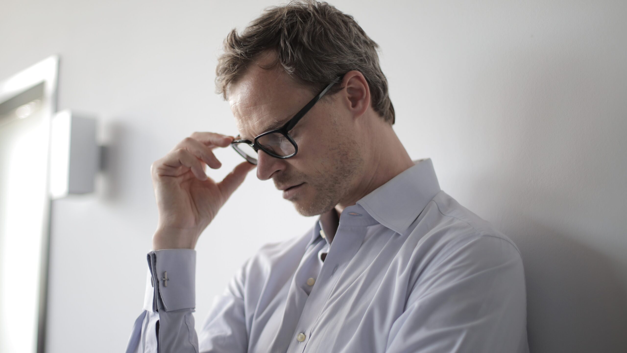 Stressed man holding his glasses in his hand