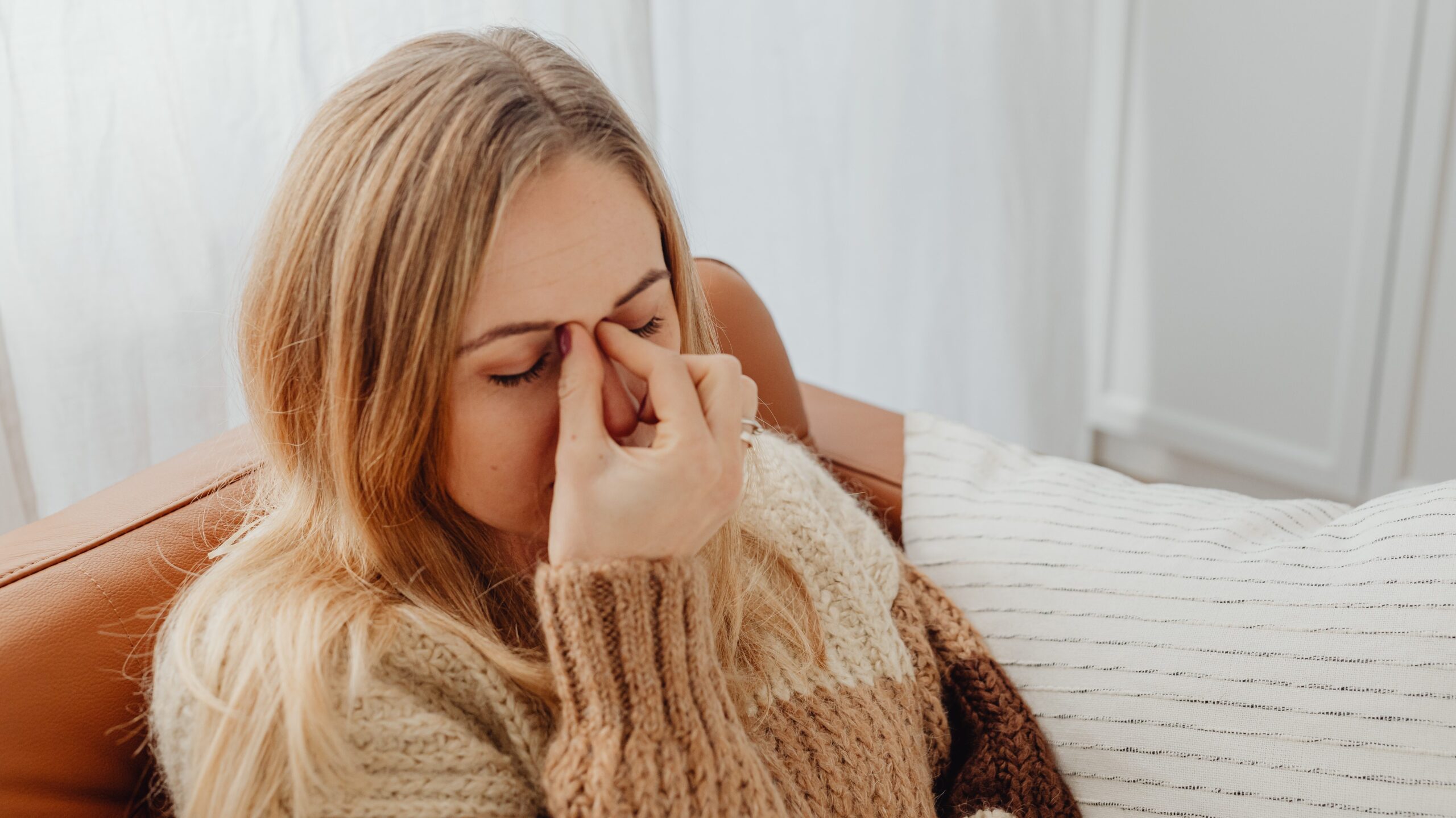 Woman holding the bridge of her nose to relieve sinus pressure