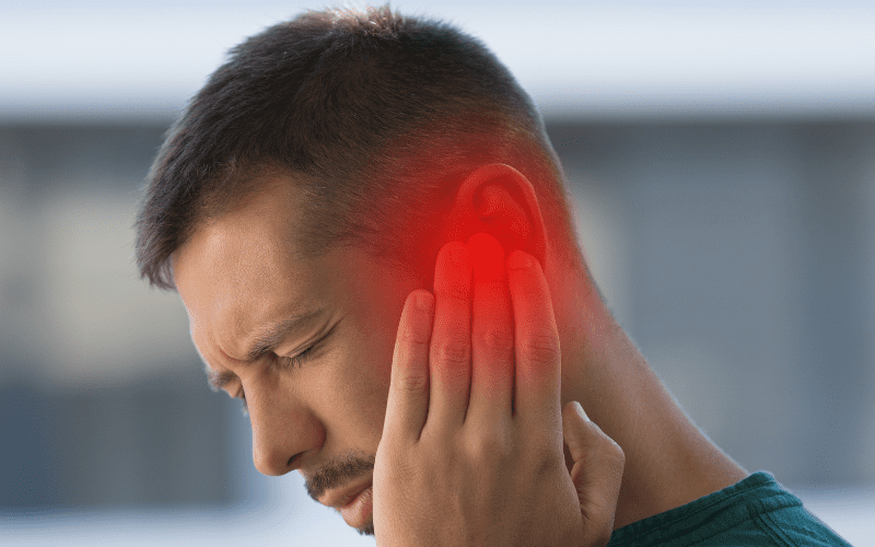 man with tinnitus holding his ear 