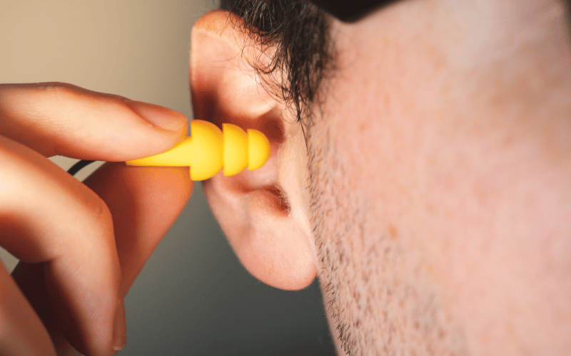 Person inserting earplugs into their ear