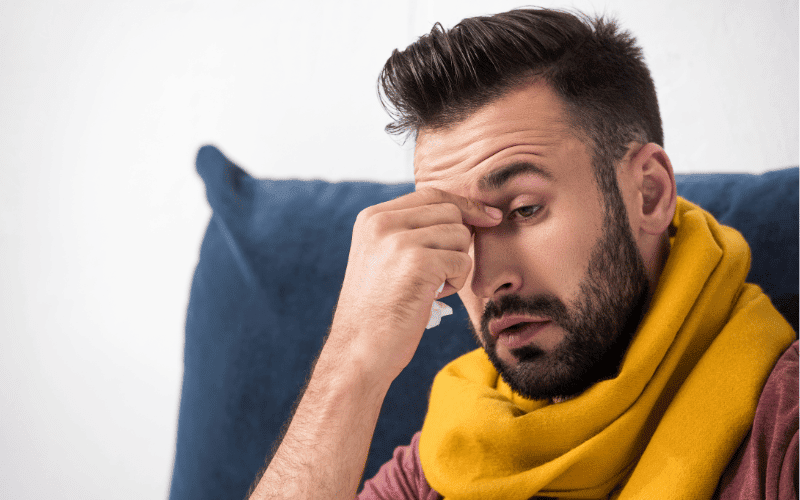 Man with a cold pinching the top of his nose