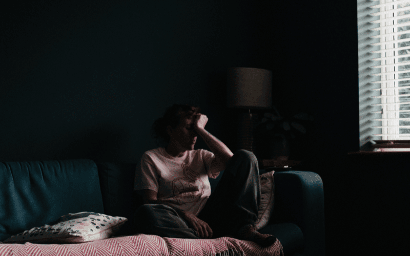 Woman sitting on the couch in a dark room