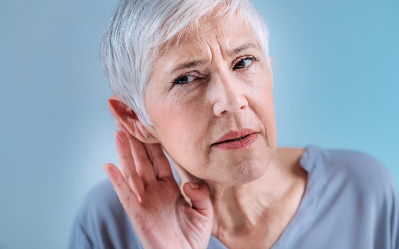 Woman with hearing loss holding her ear to increase sound